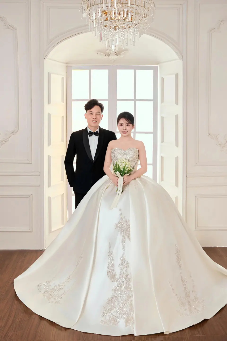 Cô dâu chú rể bên khung cửa sổ trong sảnh trắng